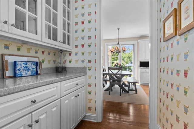 1135 Lawrence Ave, Lake Forest, IL 60045 - kitchen featuring wallpapered walls, dark wood-type flooring, white cabinets, a chandelier, and glass insert cabinets