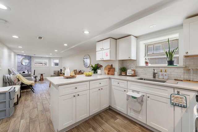 1630 N Avers Ave, Chicago, IL 60647 - kitchen featuring a peninsula, white cabinetry, decorative backsplash, light countertops, and light wood-style floors