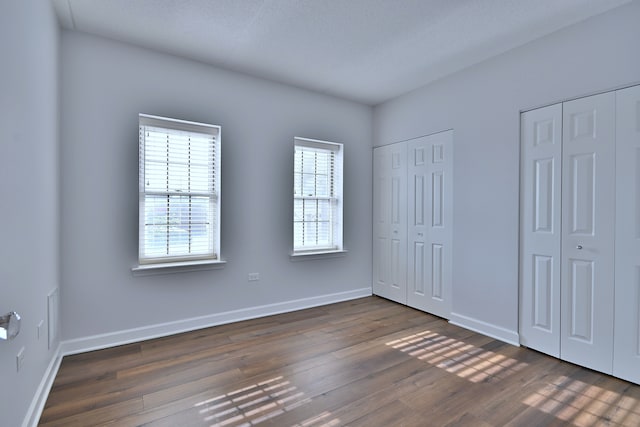 210 N Addison Ave Unit 201, Elmhurst, IL 60126 - unfurnished bedroom featuring two closets, dark wood finished floors, and baseboards