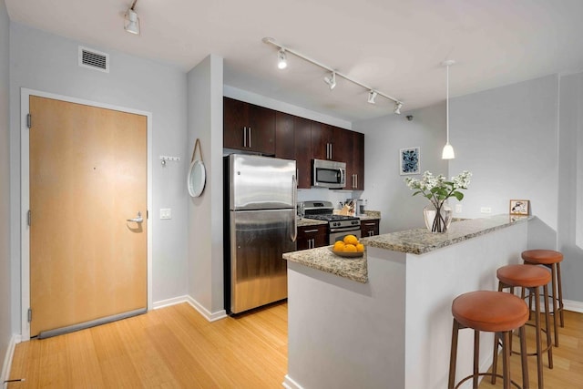 123 S Green St Unit 710B, Chicago, IL 60607 - kitchen featuring appliances with stainless steel finishes, track lighting, a kitchen bar, a peninsula, and light wood-style flooring