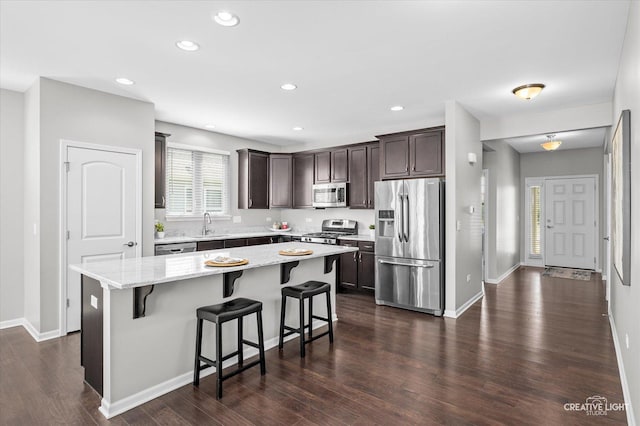 794 Suffield Ct, Oswego, IL 60543 - kitchen with appliances with stainless steel finishes, dark brown cabinets, a center island, dark wood finished floors, and a kitchen bar