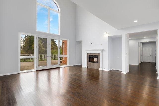 309 Dundee Rd, Barrington, IL 60010 - unfurnished living room featuring wood finished floors, plenty of natural light, french doors, a tile fireplace, and a high ceiling