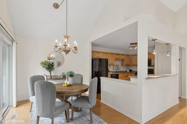 928 S Darla Ct, Waukegan, IL 60085 - dining area featuring light wood finished floors, a chandelier, vaulted ceiling, plenty of natural light, and baseboards