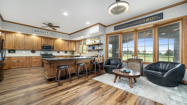2765 W Pines Rd, Oregon, IL 61061 - kitchen with black appliances, crown molding, a breakfast bar, a ceiling fan, and brown cabinetry