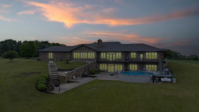 2765 W Pines Rd, Oregon, IL 61061 - back of property featuring stone siding, a patio area, a chimney, a lawn, and an outdoor pool