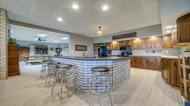 2765 W Pines Rd, Oregon, IL 61061 - kitchen featuring black appliances, light colored carpet, a sink, a kitchen bar, and a kitchen island with sink