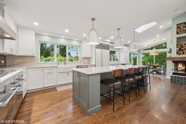 25801 Twin Pond Rd, Lake Barrington, IL 60010 - kitchen with appliances with stainless steel finishes, a center island, wall chimney range hood, wood finished floors, and recessed lighting