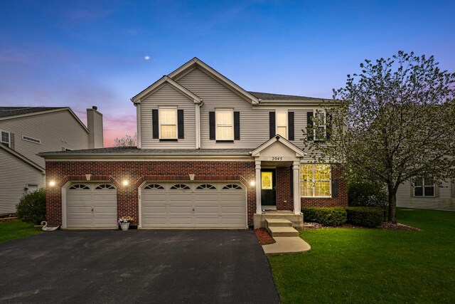 2045 Bonita Ln, Hoffman Estates, IL 60192 - traditional home featuring asphalt driveway, brick siding, a yard, and a shingled roof