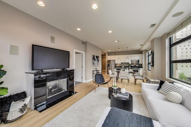 101 W Superior St Unit 501, Chicago, IL 60654 - living room featuring light wood-type flooring, a tiled fireplace, recessed lighting, and baseboards