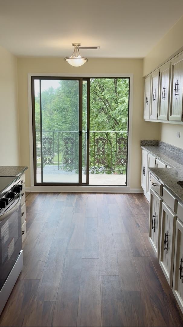 5501 Lincoln Ave Unit 405, Morton Grove, IL 60053 - kitchen featuring stainless steel electric range, white cabinetry, healthy amount of natural light, and dark wood-type flooring
