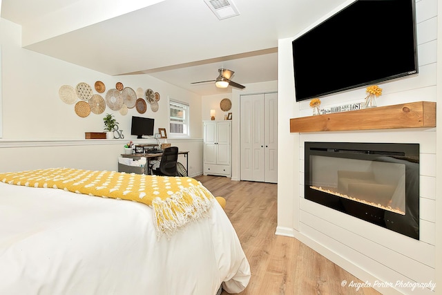 155 Shadowbrook Dr, Capron, IL 61012 - bedroom with light wood-style flooring, a glass covered fireplace, ceiling fan, and a closet