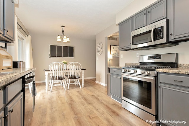 155 Shadowbrook Dr, Capron, IL 61012 - kitchen featuring appliances with stainless steel finishes, gray cabinets, a chandelier, light countertops, and light wood-style flooring