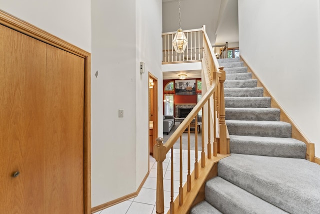 11234 Lakefield Dr, Orland Park, IL 60467 - stairs with a chandelier, a high ceiling, tile patterned flooring, baseboards, and a fireplace
