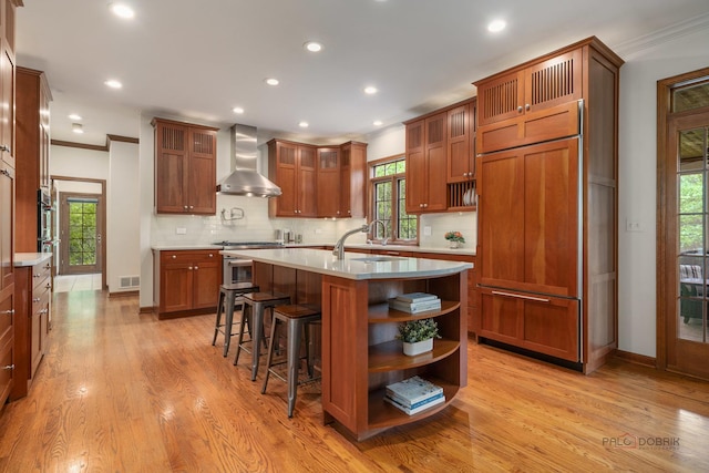 1602 Wickham Ct, Libertyville, IL 60048 - kitchen with wall chimney range hood, paneled fridge, ornamental molding, light countertops, and light wood finished floors