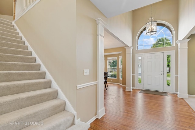 18861 W Aspen Ct, Lake Villa, IL 60046 - foyer featuring ornate columns, wood-type flooring, a chandelier, and a high ceiling