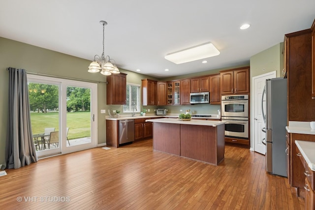 18861 W Aspen Ct, Lake Villa, IL 60046 - kitchen featuring appliances with stainless steel finishes, light countertops, hardwood / wood-style floors, a chandelier, and glass insert cabinets
