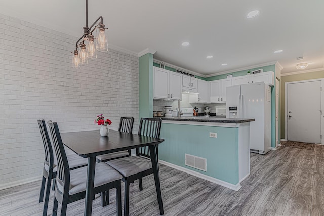 2367 Camden Bay, Elgin, IL 60123 - kitchen featuring white fridge with ice dispenser, dark countertops, ornamental molding, light wood-type flooring, and brick wall