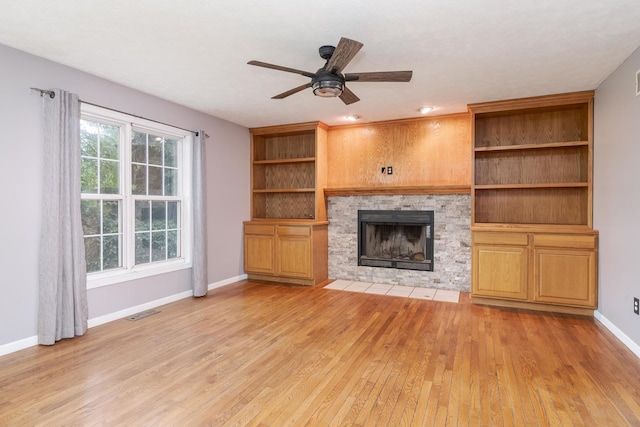 102 Merganser Ct, Downs, IL 61736 - unfurnished living room featuring light wood-type flooring, a stone fireplace, ceiling fan, and baseboards
