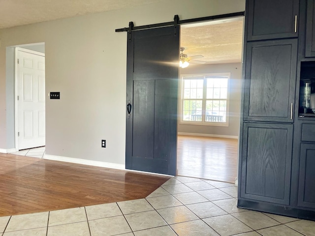 102 Merganser Ct, Downs, IL 61736 - spare room featuring light tile patterned floors, a barn door, baseboards, and ceiling fan