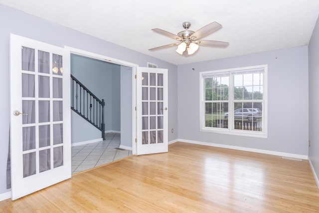 102 Merganser Ct, Downs, IL 61736 - empty room featuring stairway, baseboards, wood finished floors, a ceiling fan, and french doors