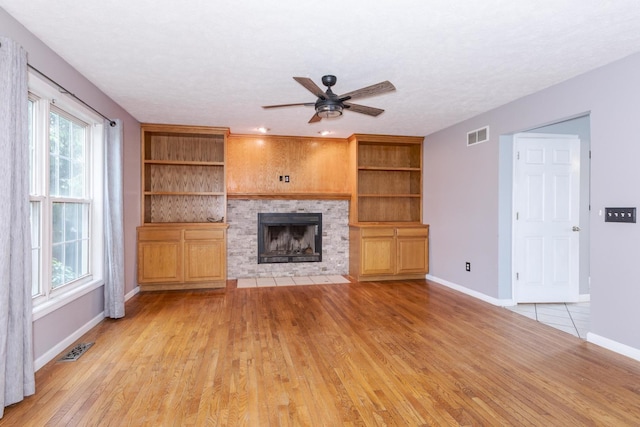 102 Merganser Ct, Downs, IL 61736 - unfurnished living room featuring a ceiling fan, baseboards, a fireplace, and light wood-style floors
