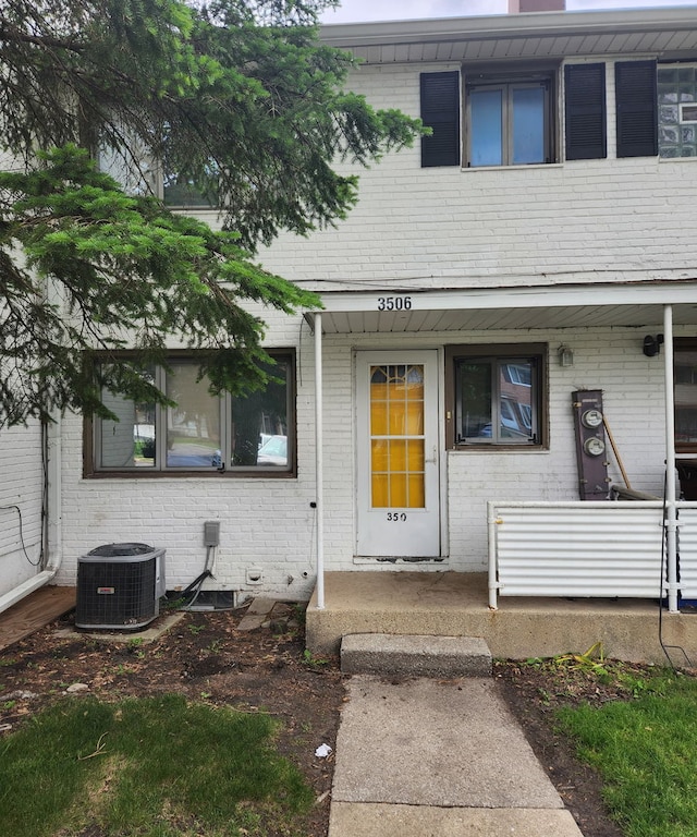view of exterior entry featuring brick siding and covered porch