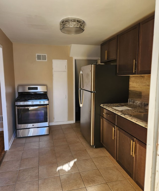 kitchen with stainless steel appliances, dark brown cabinets, and light tile patterned floors