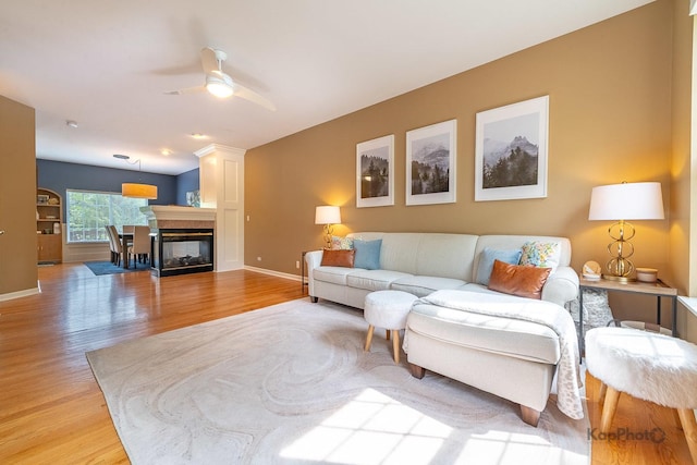 155 Willow Blvd, Willow Springs, IL 60480 - living room featuring light wood-style floors, a ceiling fan, baseboards, and a multi sided fireplace
