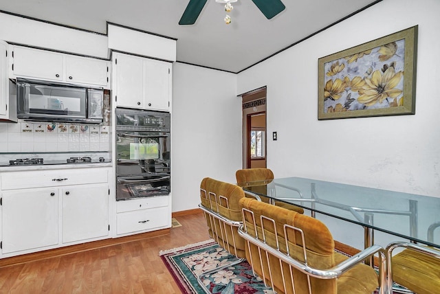 302 Wabash Ave, Campus, IL 60920 - kitchen with black appliances, a warming drawer, white cabinets, tasteful backsplash, and wood finished floors