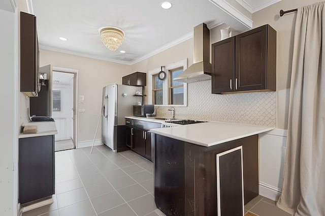 3731 Maple Ave, Berwyn, IL 60402 - kitchen featuring wall chimney exhaust hood, dark brown cabinetry, a peninsula, decorative backsplash, and freestanding refrigerator