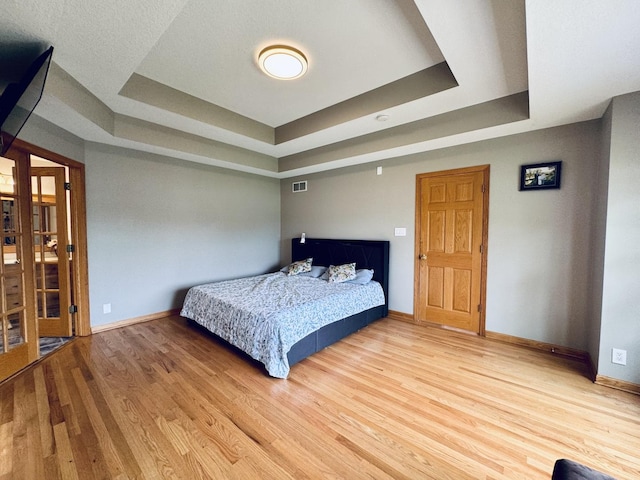 1102 Brian Dr, Manteno, IL 60950 - bedroom featuring a tray ceiling, baseboards, and light wood-type flooring