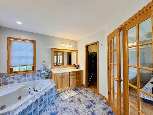 1102 Brian Dr, Manteno, IL 60950 - bathroom featuring french doors, vanity, a tub with jets, a walk in closet, and recessed lighting