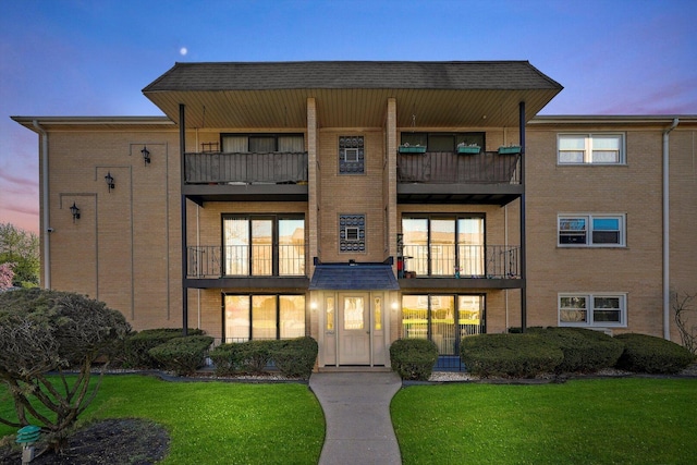 6568 W Roscoe St Unit 2N, Chicago, IL 60634 - rear view of house featuring a balcony, brick siding, and a lawn