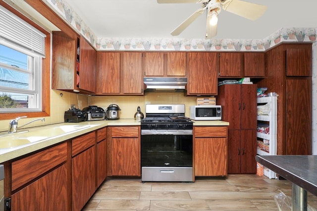 6568 W Roscoe St Unit 2N, Chicago, IL 60634 - kitchen with stainless steel gas stove, under cabinet range hood, white microwave, a sink, and light countertops