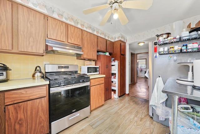 6568 W Roscoe St Unit 2N, Chicago, IL 60634 - kitchen with stainless steel appliances, under cabinet range hood, light countertops, decorative backsplash, and light wood finished floors