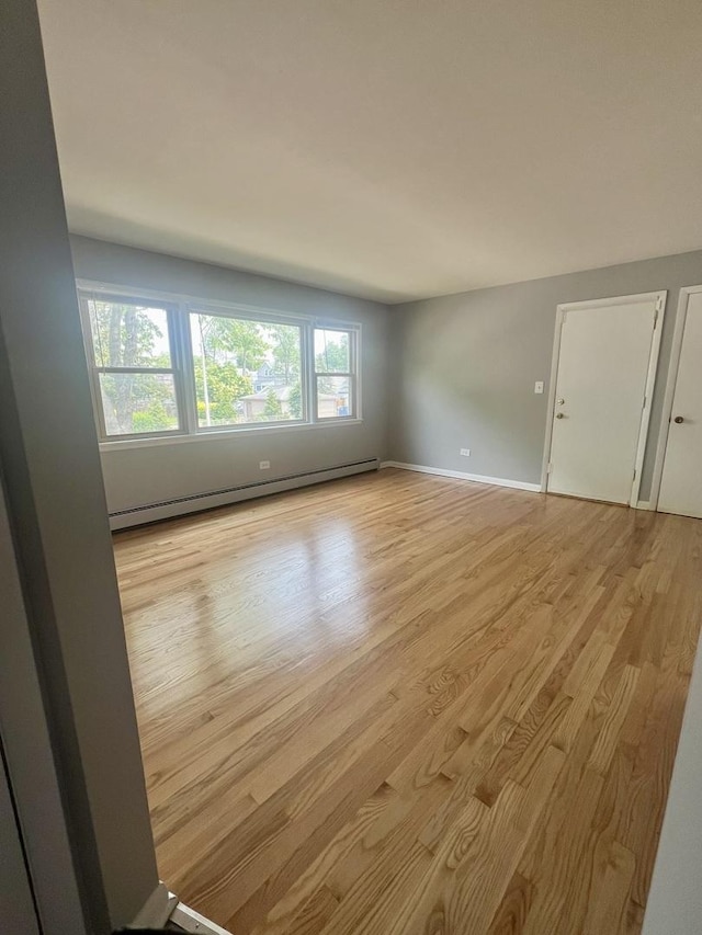 1100 Hannah Ave Unit 104, Forest Park, IL 60130 - empty room with a baseboard heating unit, light wood-style floors, and baseboards