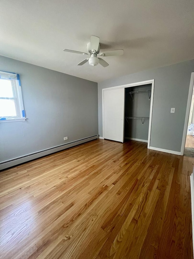1100 Hannah Ave Unit 104, Forest Park, IL 60130 - unfurnished bedroom featuring baseboard heating, a closet, wood finished floors, ceiling fan, and baseboards
