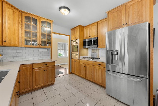 5111 S Luna Ave, Chicago, IL 60638 - kitchen featuring appliances with stainless steel finishes, decorative backsplash, light countertops, light tile patterned floors, and glass insert cabinets