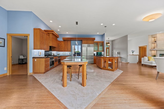 515 Stone Ridge Ln, Cherry Valley, IL 61016 - kitchen featuring appliances with stainless steel finishes, a kitchen island with sink, light wood-style floors, brown cabinets, and recessed lighting