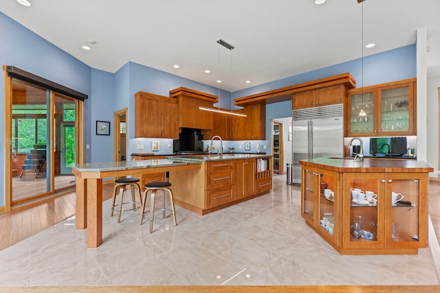 515 Stone Ridge Ln, Cherry Valley, IL 61016 - kitchen with a large island with sink, built in fridge, brown cabinets, and recessed lighting