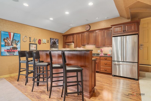 36955 N Fox Hill Dr, Wadsworth, IL 60083 - kitchen featuring stainless steel refrigerator, light wood-style floors, a breakfast bar area, dark countertops, and vaulted ceiling