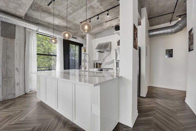 1033 W 14th Pl Unit 337, Chicago, IL 60608 - kitchen featuring white cabinetry, baseboards, wall chimney exhaust hood, and track lighting