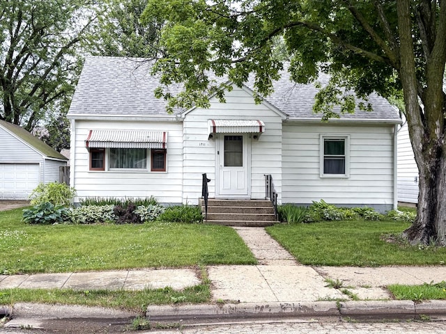 1711 17th Ave, Sterling, IL 61081 - view of front of property with a shingled roof, a front yard, a detached garage, and an outbuilding
