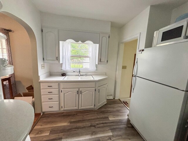 1711 17th Ave, Sterling, IL 61081 - kitchen featuring white appliances, a sink, dark wood-type flooring, white cabinets, and arched walkways