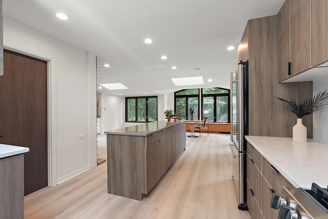 71 Graymoor Ln, Olympia Fields, IL 60461 - kitchen featuring modern cabinets, a skylight, light wood finished floors, a kitchen island, and freestanding refrigerator