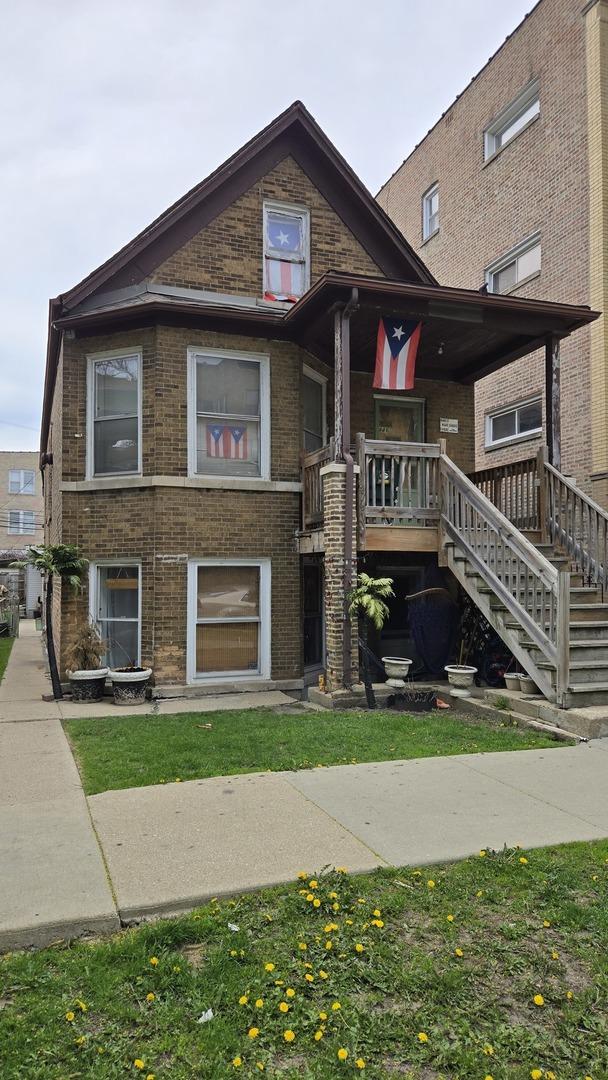 view of front of house with stairs, brick siding, and a porch