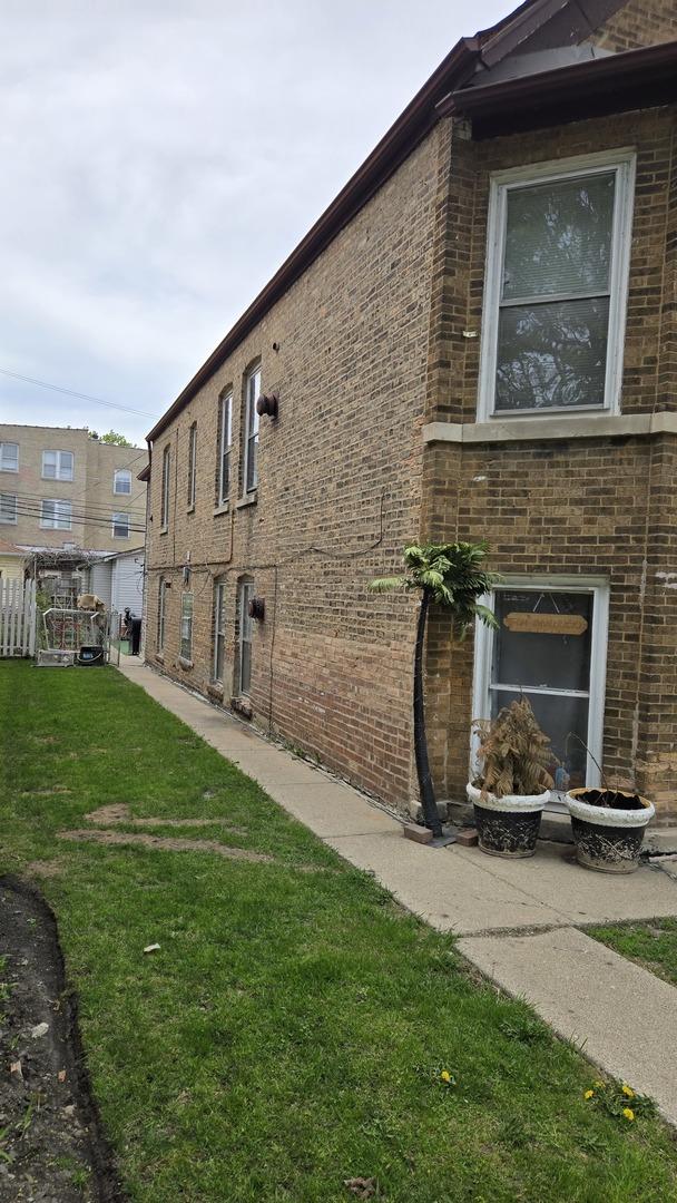 view of side of property with brick siding and a yard