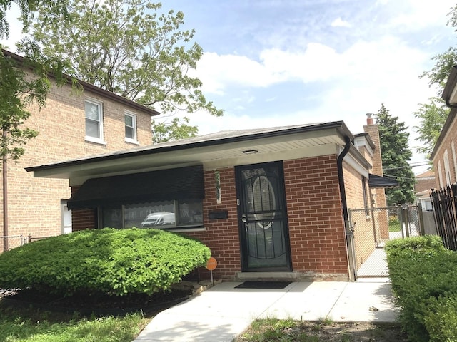 10507 S Indiana Ave, Chicago, IL 60628 - view of exterior entry featuring brick siding, a chimney, and a gate