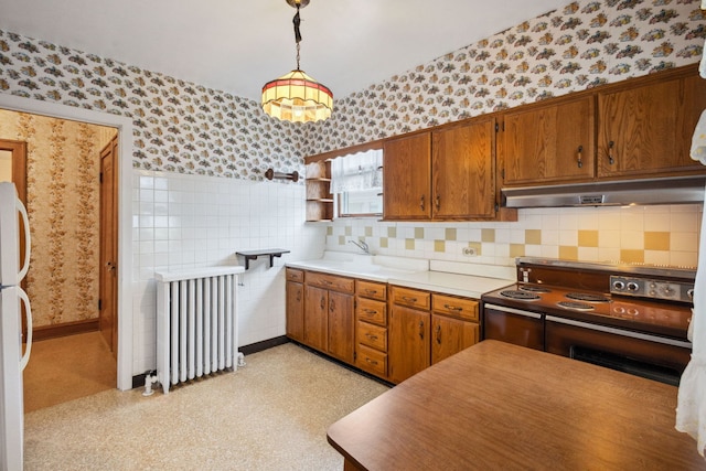 3006 N Sayre Ave, Chicago, IL 60634 - kitchen with wallpapered walls, radiator, brown cabinets, electric stove, and under cabinet range hood