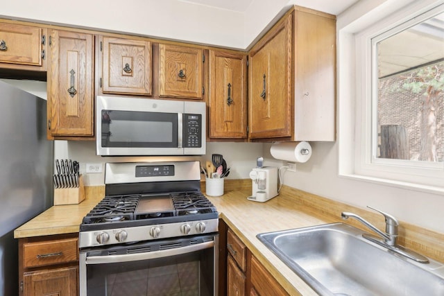 68 Pier Dr Unit 102, Westmont, IL 60559 - kitchen with appliances with stainless steel finishes, a sink, light countertops, and brown cabinetry